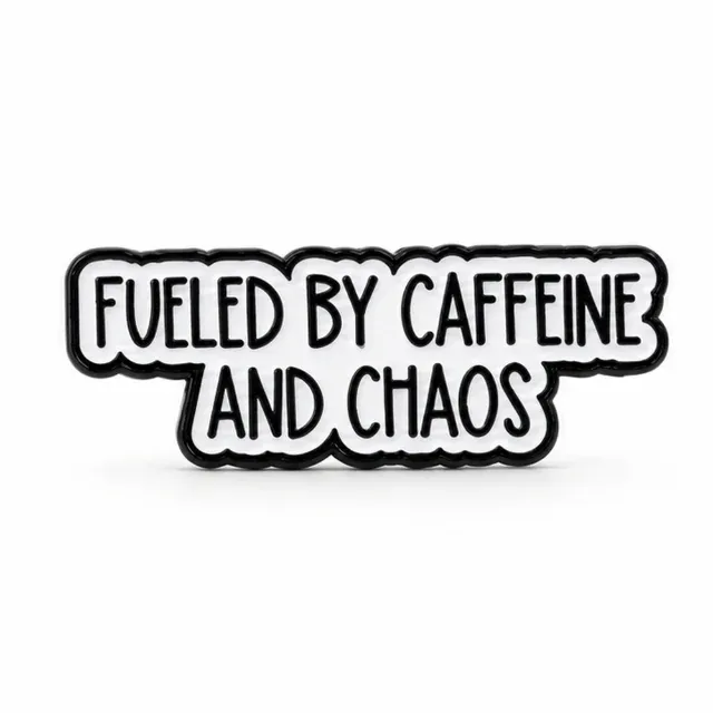 White Fuelled by Caffeine and Chaos enamel pin with black lettering and outline on a plain white background.
